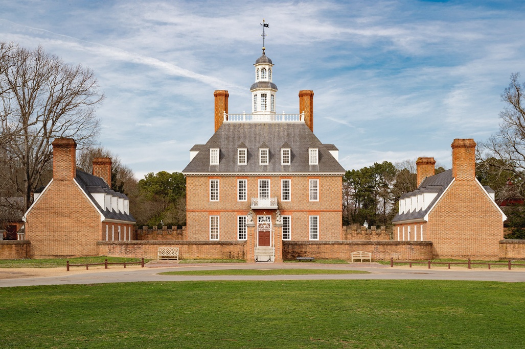 The Governor's Palace at Colonial Williamsburg, a brick Georgian building with a cupola, seen across an open lawn.